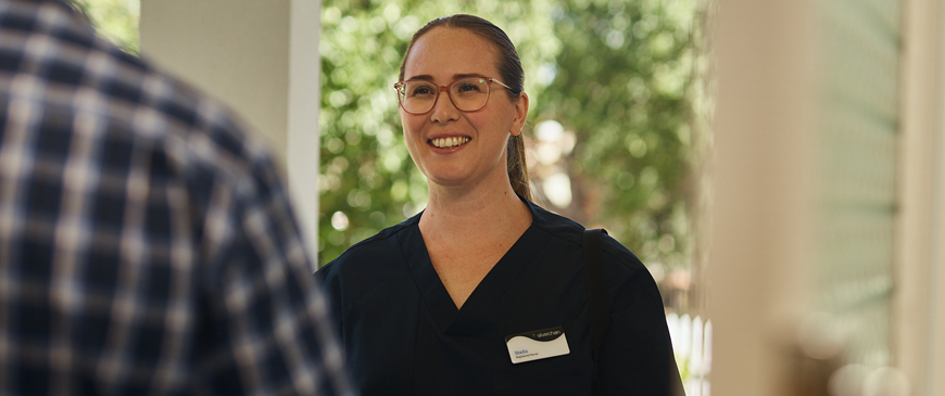 A client greets a smiling nurse at his front door